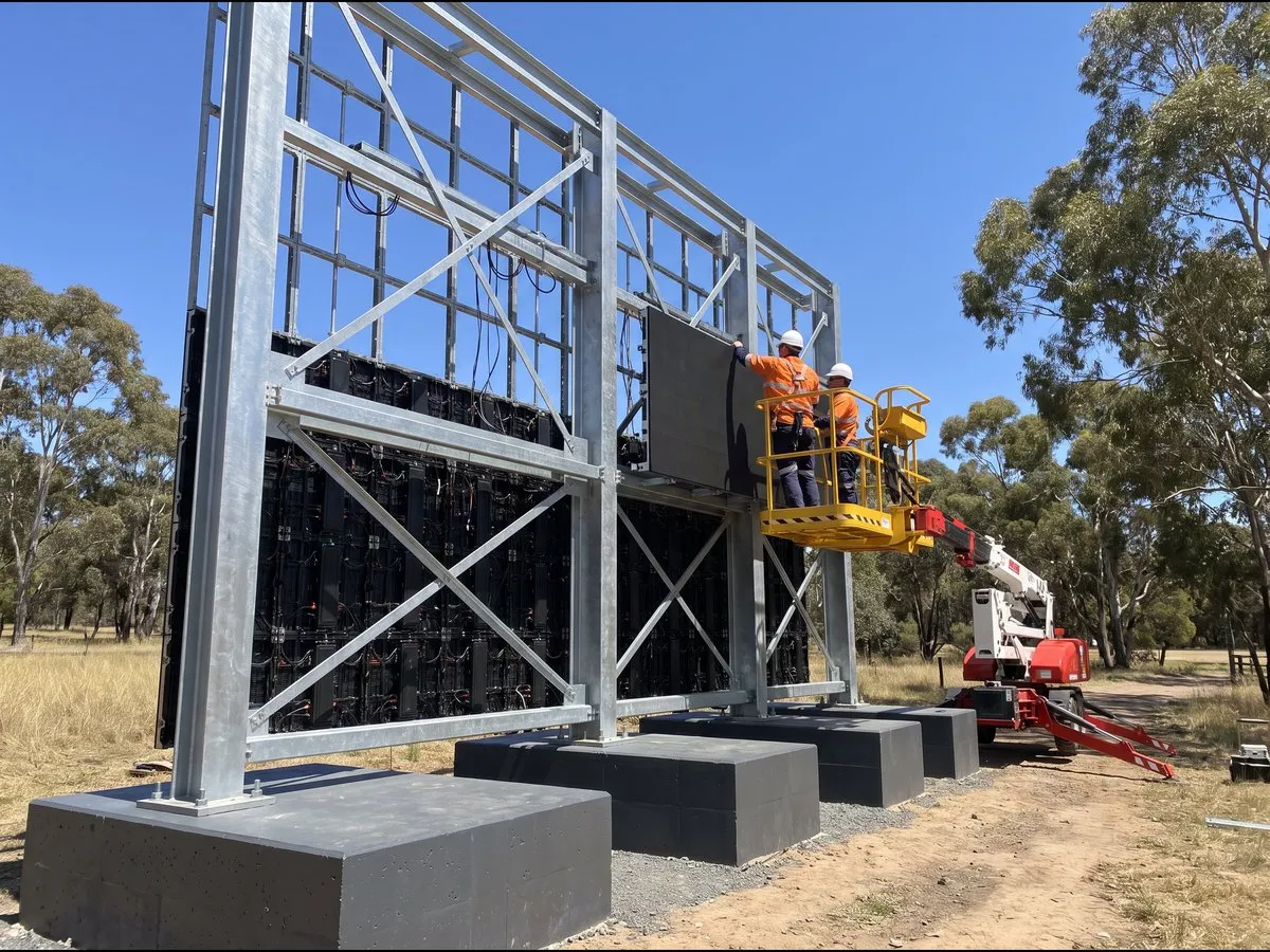 Illustration: installers fitting LED cabinets to a galvanised steel frame on concrete footings