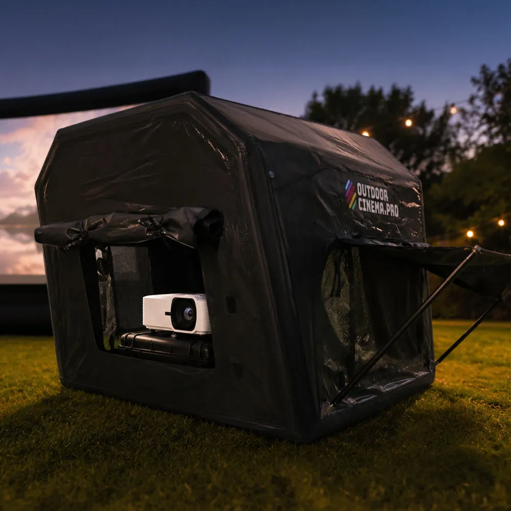 An inflatable black projector weather tent on grass at dusk, a projector inside projecting out the front opening, with a propped side vent