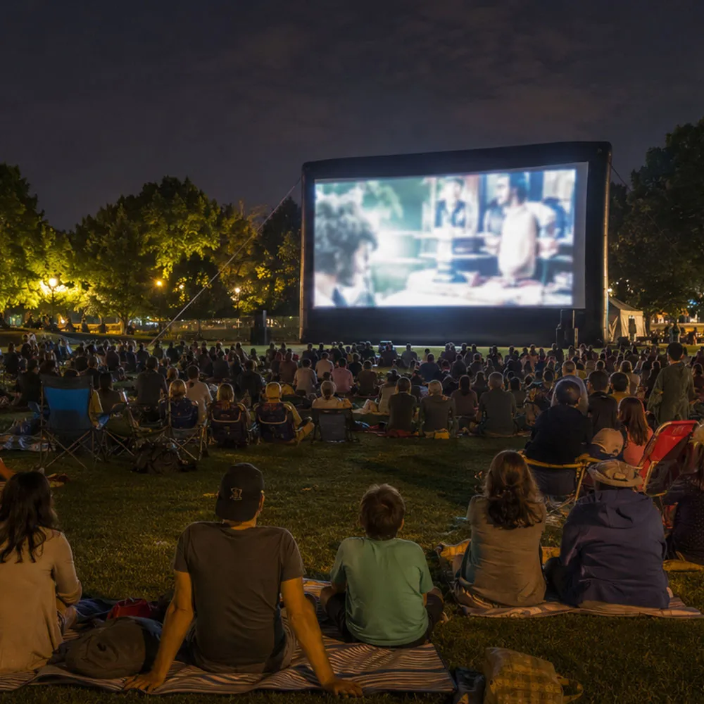 A large crowd on the grass at a movie in the park event at night