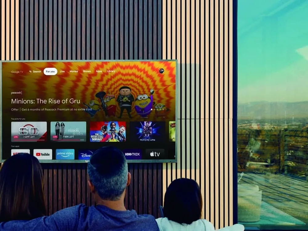 A family watching the Google TV home screen on a wall-mounted outdoor television
